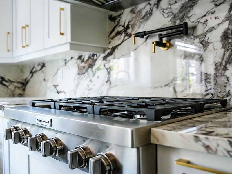 Close-up of the veined marble counter and backsplash meeting the gas cooktop