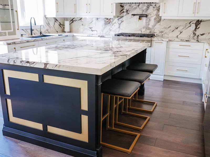 Navy island with brass-toned inlay under a marble top, with upholstered stools
